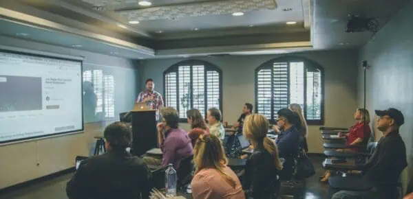a group of people in a room with a projector screen in an academic institution for an article about transcription