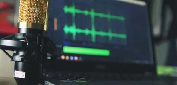 Gold Condenser Microphone Near Laptop Computer and is conducting voice transcription