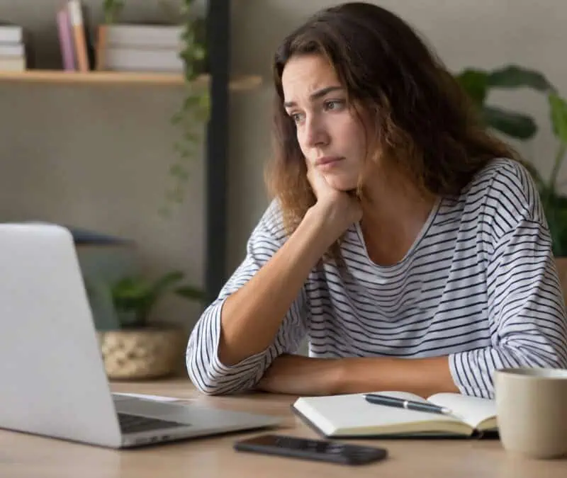Woman focused on her laptop, working on transcription tasks at home.