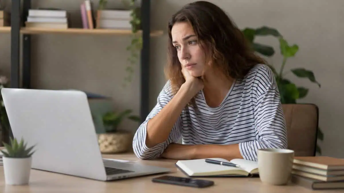 Woman focused on her laptop, working on transcription tasks at home.